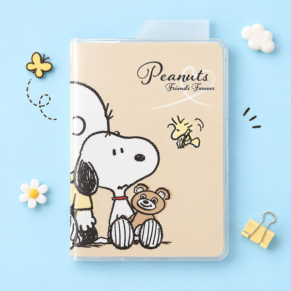 A beige 2027 schedule book printed with Peanuts characters, including Snoopy, Woodstock, and the text 'Peanuts Friends Forever,' styled on a light blue background with small decorative flowers, clouds, and binder clips. 